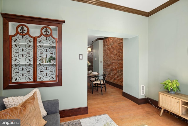 interior space featuring light wood finished floors, brick wall, visible vents, and crown molding