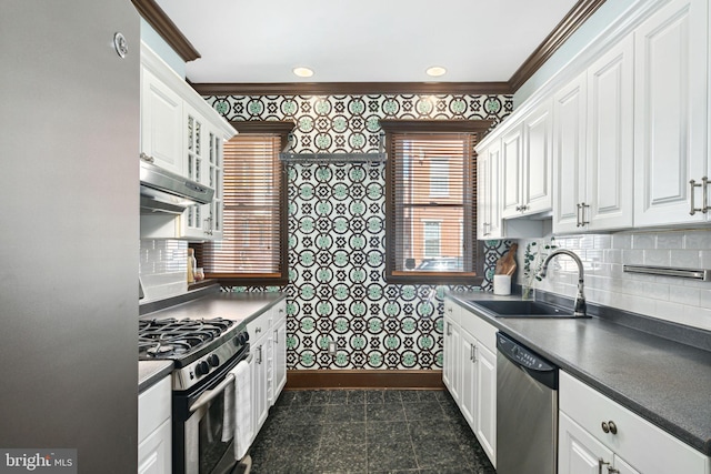 kitchen with dark countertops, stainless steel appliances, under cabinet range hood, granite finish floor, and a sink