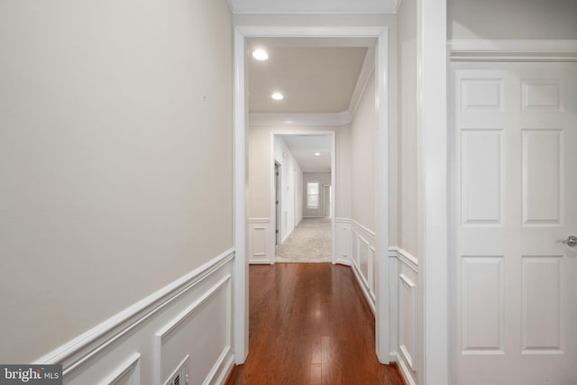 hallway with dark wood-style flooring, recessed lighting, a decorative wall, ornamental molding, and wainscoting