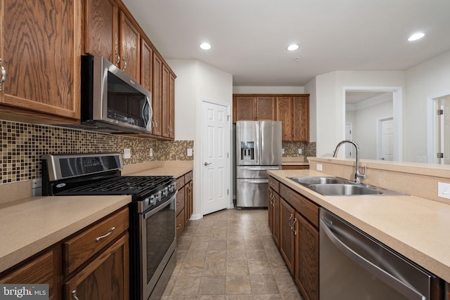 kitchen with recessed lighting, stainless steel appliances, a sink, light countertops, and backsplash