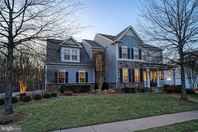 view of front facade with stone siding and a front lawn