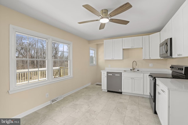 kitchen with visible vents, light countertops, stainless steel appliances, white cabinetry, and a sink