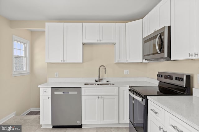 kitchen featuring a sink, white cabinets, baseboards, and stainless steel appliances