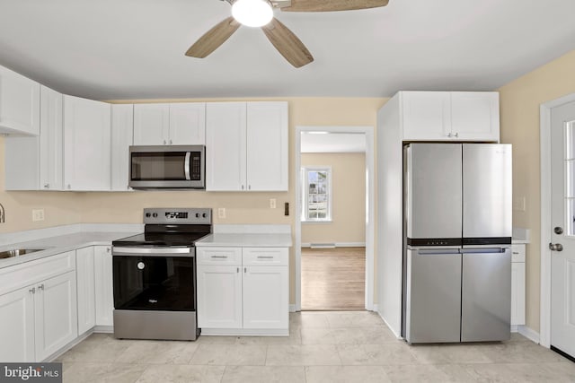 kitchen with ceiling fan, light countertops, appliances with stainless steel finishes, white cabinetry, and a sink