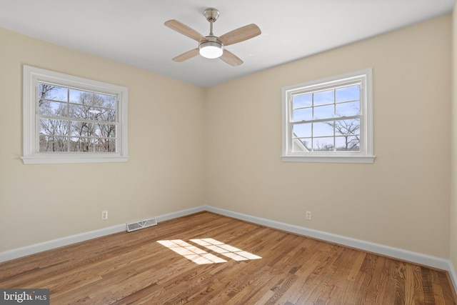 spare room with visible vents, baseboards, and wood finished floors