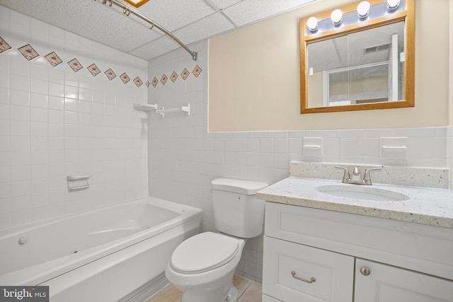 bathroom featuring toilet, tile walls, a paneled ceiling, bathing tub / shower combination, and vanity