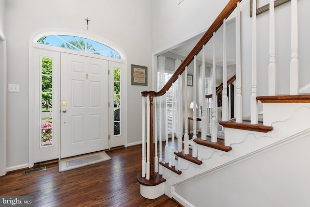 foyer featuring stairway, visible vents, baseboards, a towering ceiling, and wood finished floors