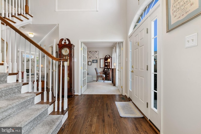foyer with stairway, wood finished floors, a wealth of natural light, and a towering ceiling