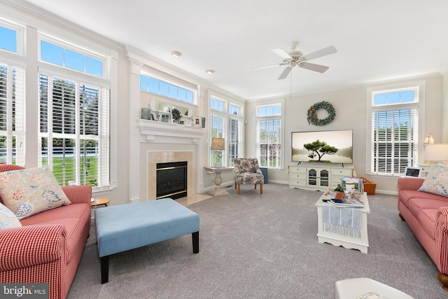 living area featuring a fireplace with flush hearth, baseboards, carpet floors, ornamental molding, and a ceiling fan