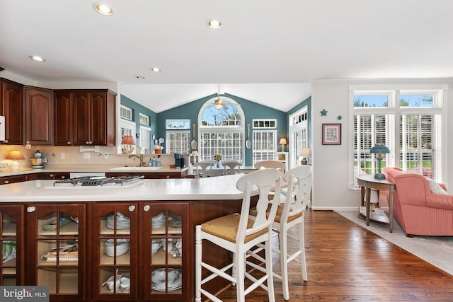 kitchen featuring a sink, light countertops, white gas cooktop, vaulted ceiling, and dark wood finished floors