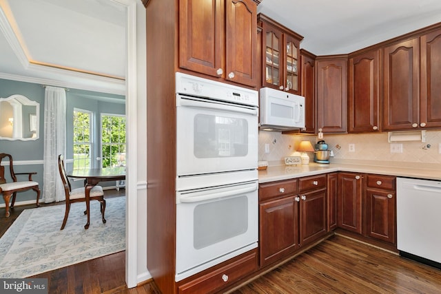 kitchen featuring glass insert cabinets, white appliances, dark wood-type flooring, backsplash, and light countertops