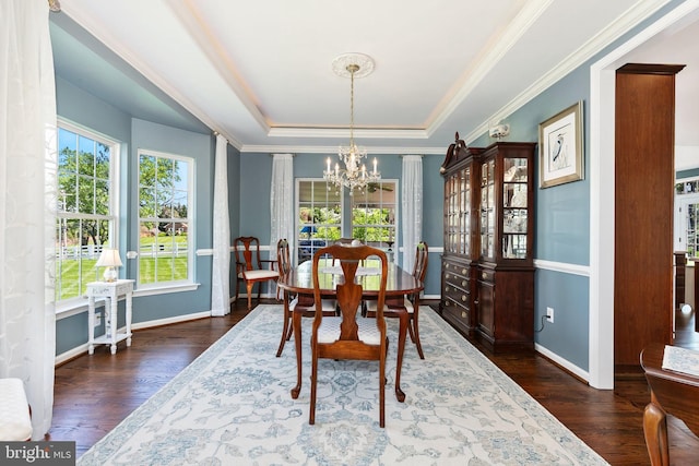 dining area featuring a notable chandelier, a tray ceiling, baseboards, ornamental molding, and wood finished floors