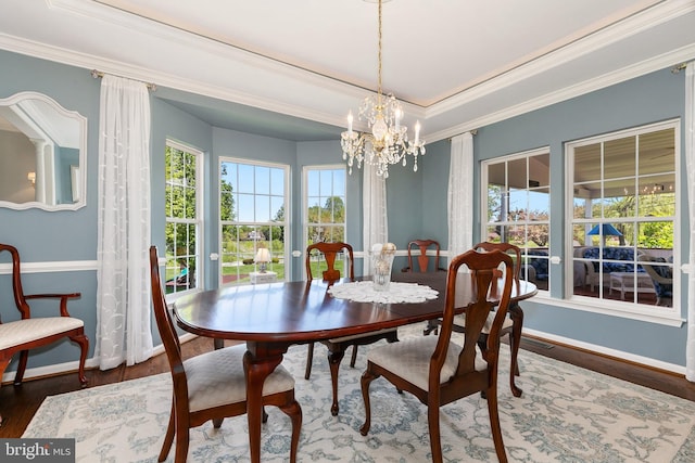 dining space featuring an inviting chandelier, a raised ceiling, crown molding, baseboards, and wood finished floors