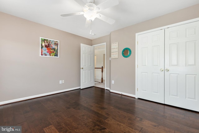 unfurnished bedroom featuring dark wood-style flooring, ceiling fan, a closet, and baseboards
