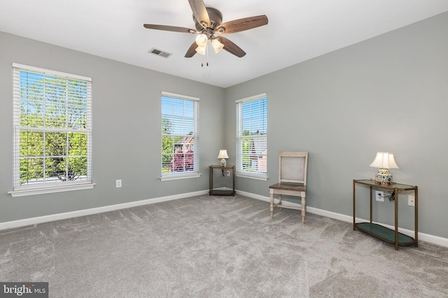 living area featuring carpet flooring, visible vents, ceiling fan, and baseboards