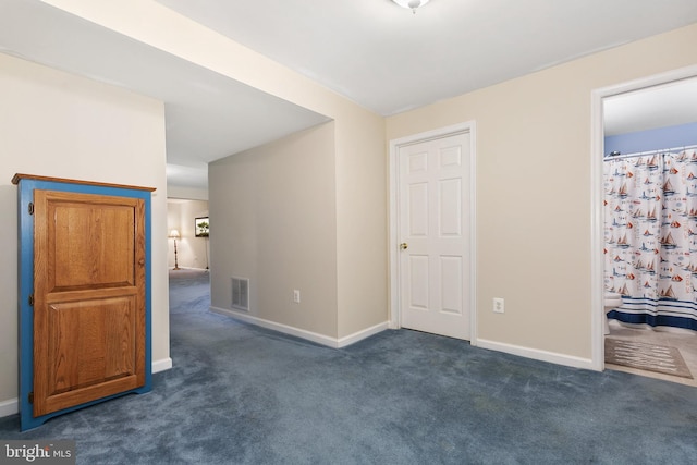 unfurnished room featuring visible vents, dark colored carpet, and baseboards