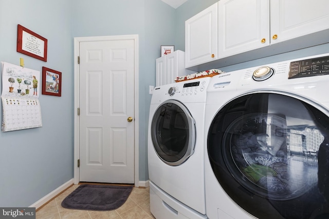 washroom featuring light tile patterned floors, washing machine and dryer, cabinet space, and baseboards