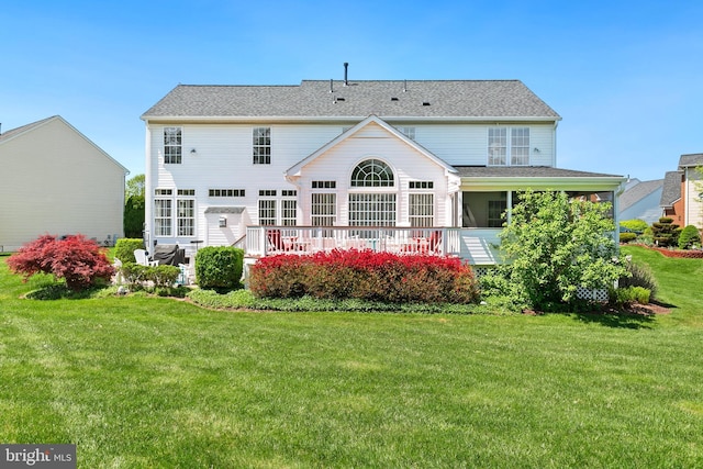 rear view of house featuring a wooden deck and a yard