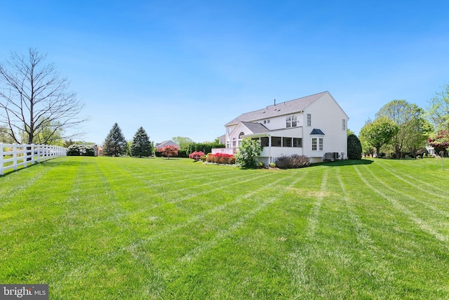 view of yard with a sunroom, central AC, and fence