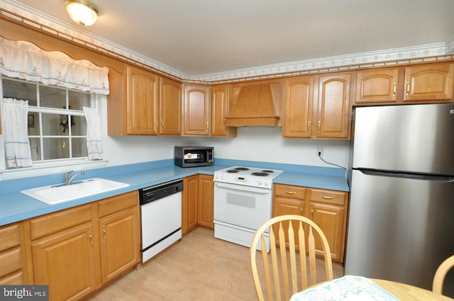 kitchen featuring light countertops, appliances with stainless steel finishes, light wood-style floors, custom exhaust hood, and a sink