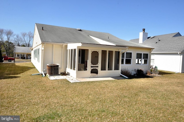 back of house with a yard, central AC unit, a chimney, and a sunroom