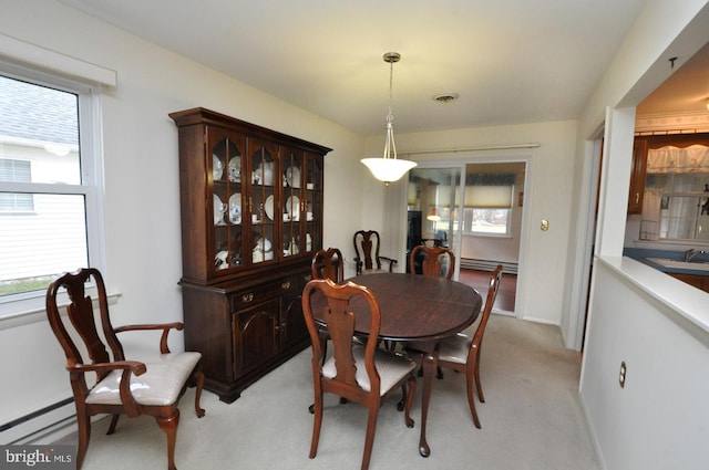 dining area with light colored carpet, visible vents, a wealth of natural light, and a baseboard radiator