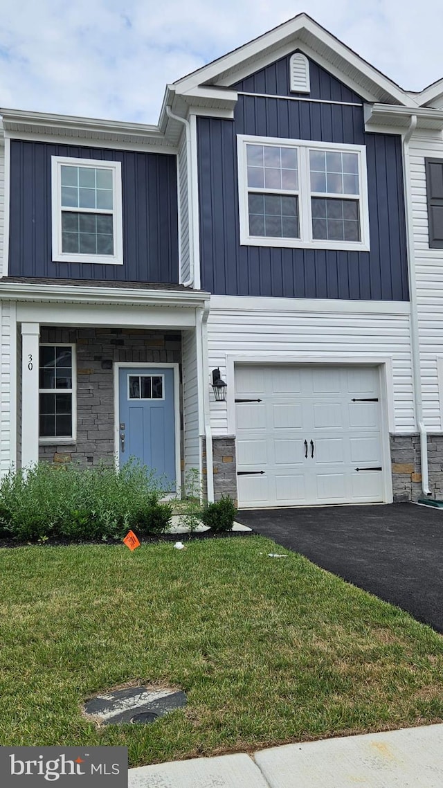 view of front facade featuring board and batten siding, stone siding, an attached garage, and aphalt driveway