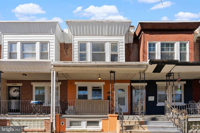 multi unit property featuring covered porch and brick siding