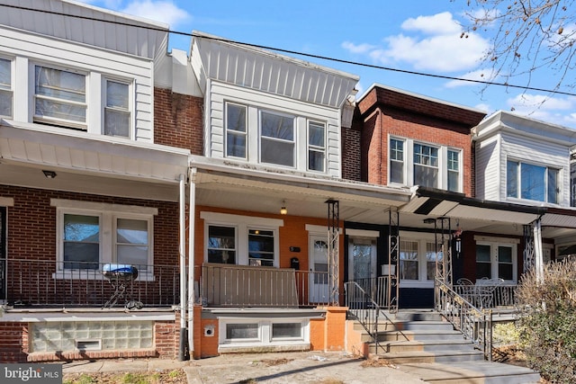 townhome / multi-family property featuring a porch and brick siding