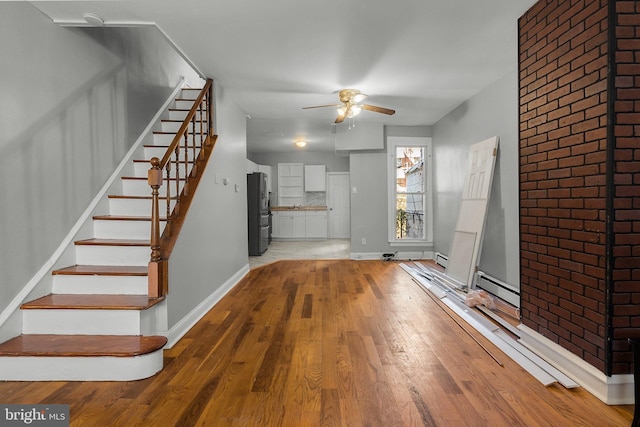 interior space with stairway, baseboard heating, light wood-type flooring, and baseboards