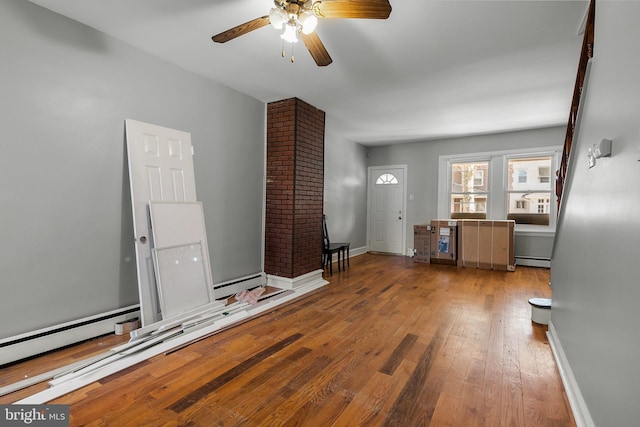 interior space with hardwood / wood-style floors, baseboard heating, a baseboard heating unit, a ceiling fan, and baseboards