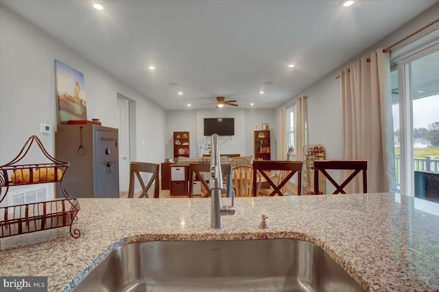 kitchen featuring ceiling fan, light stone counters, a sink, and recessed lighting