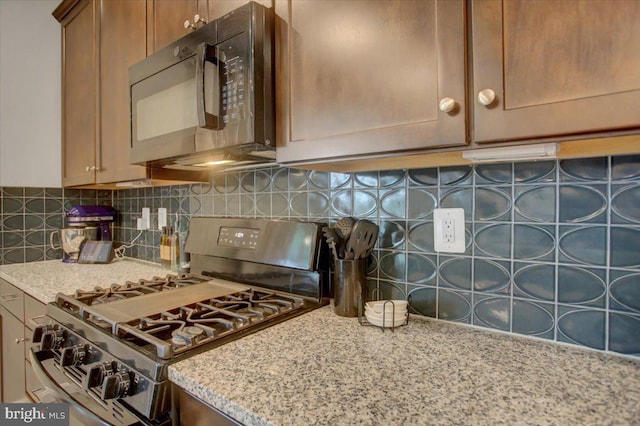 kitchen featuring tasteful backsplash, gas stove, black microwave, and light stone counters