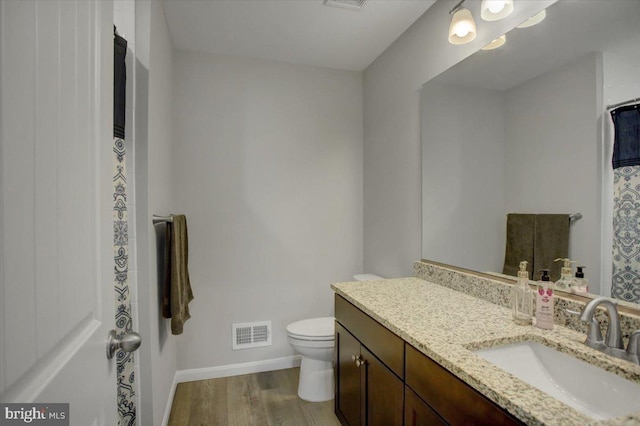 full bathroom featuring toilet, wood finished floors, vanity, visible vents, and baseboards