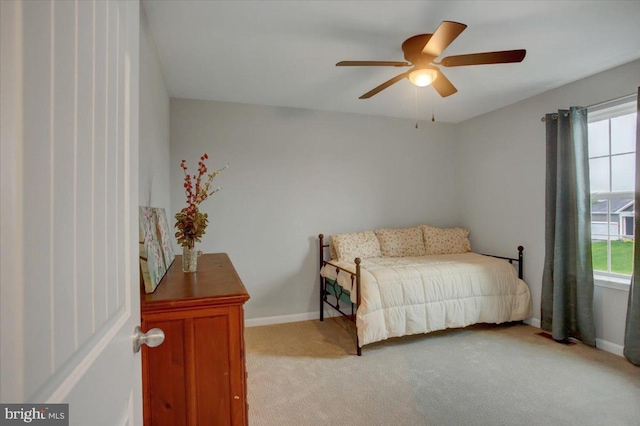 bedroom with light carpet, multiple windows, baseboards, and a ceiling fan