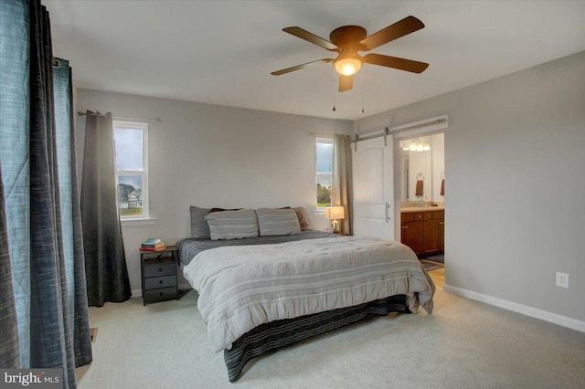 bedroom with baseboards, connected bathroom, a ceiling fan, and light colored carpet