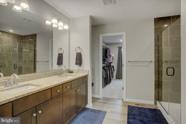 bathroom featuring a stall shower, a walk in closet, a sink, and double vanity