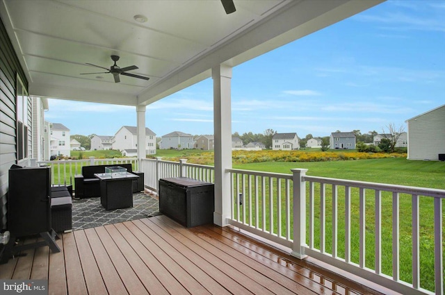 deck featuring a ceiling fan, a residential view, and a yard