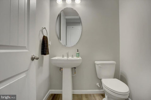 bathroom with toilet, baseboards, and wood finished floors