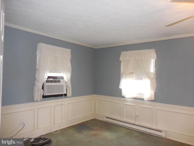 carpeted spare room with a wealth of natural light, a wainscoted wall, and baseboard heating