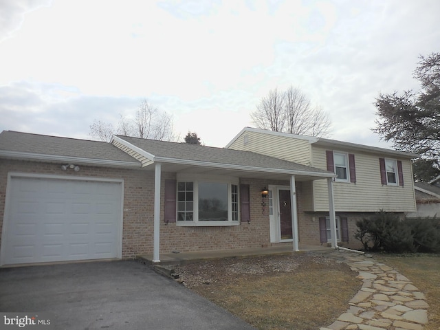 split level home with an attached garage, a shingled roof, aphalt driveway, and brick siding