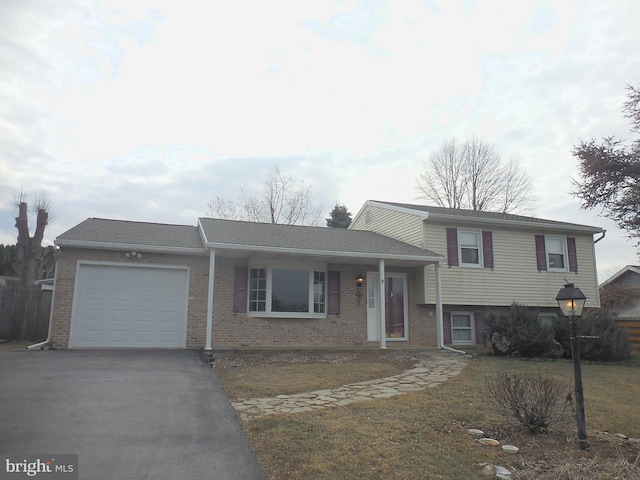 split level home with a garage, driveway, and brick siding