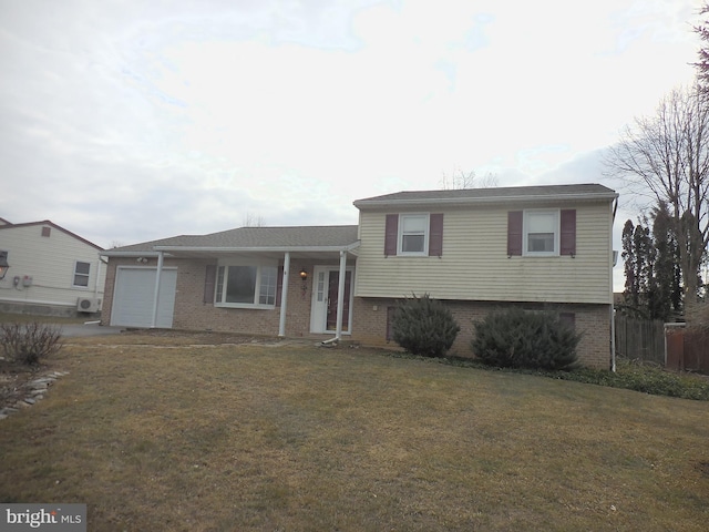 split level home featuring an attached garage, a front yard, fence, and brick siding