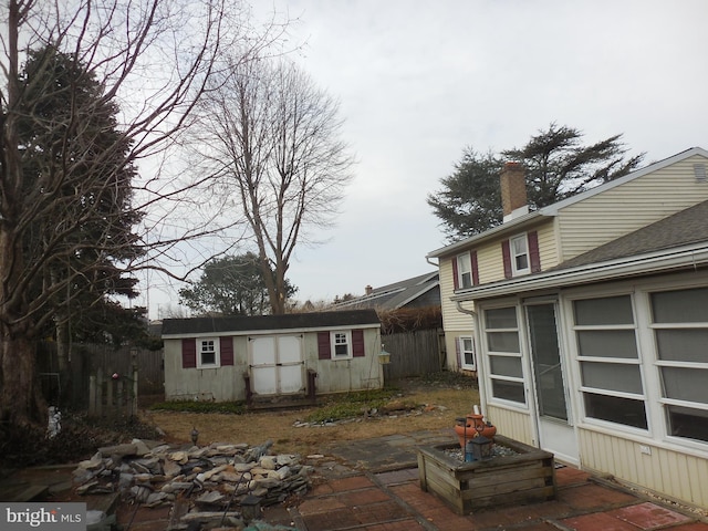 view of side of home with an outbuilding, fence, a chimney, and a shed