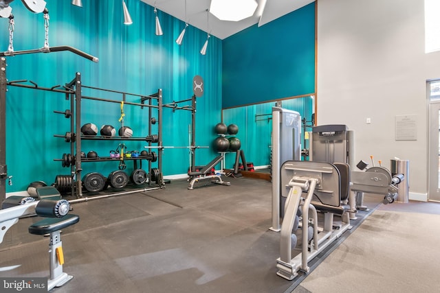 gym with a high ceiling and baseboards