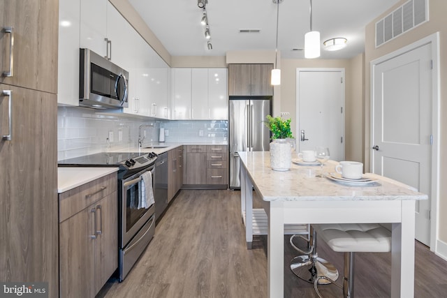 kitchen featuring visible vents, stainless steel appliances, modern cabinets, tasteful backsplash, and a center island