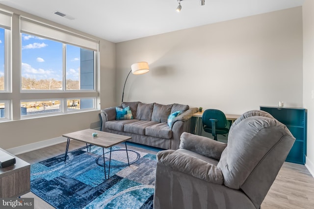 living area featuring visible vents, baseboards, and wood finished floors