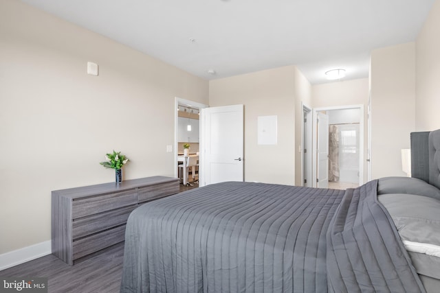 bedroom with connected bathroom, baseboards, and wood finished floors