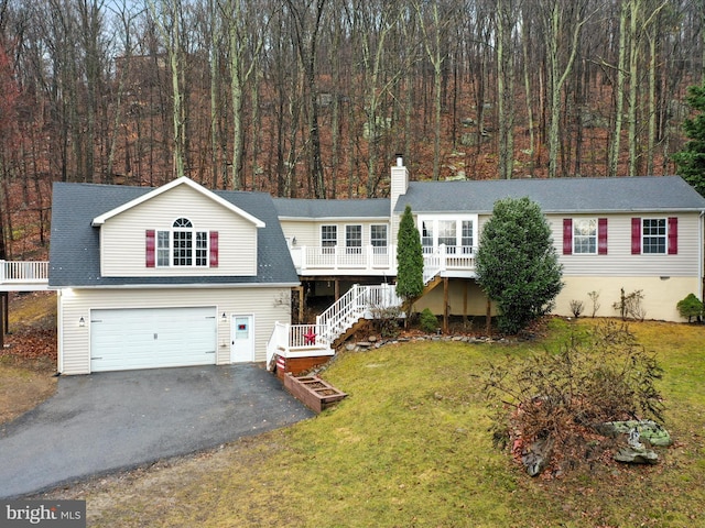 view of front of property featuring an attached garage, driveway, stairway, a chimney, and a front yard