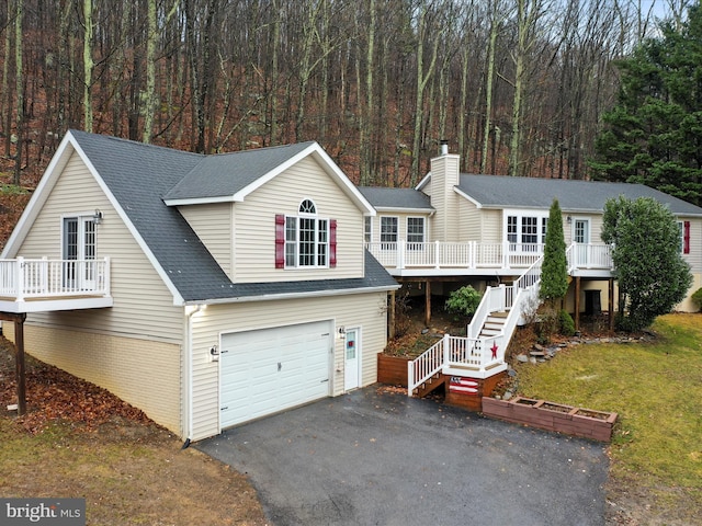 view of front of house featuring stairway, aphalt driveway, an attached garage, a wooded view, and brick siding